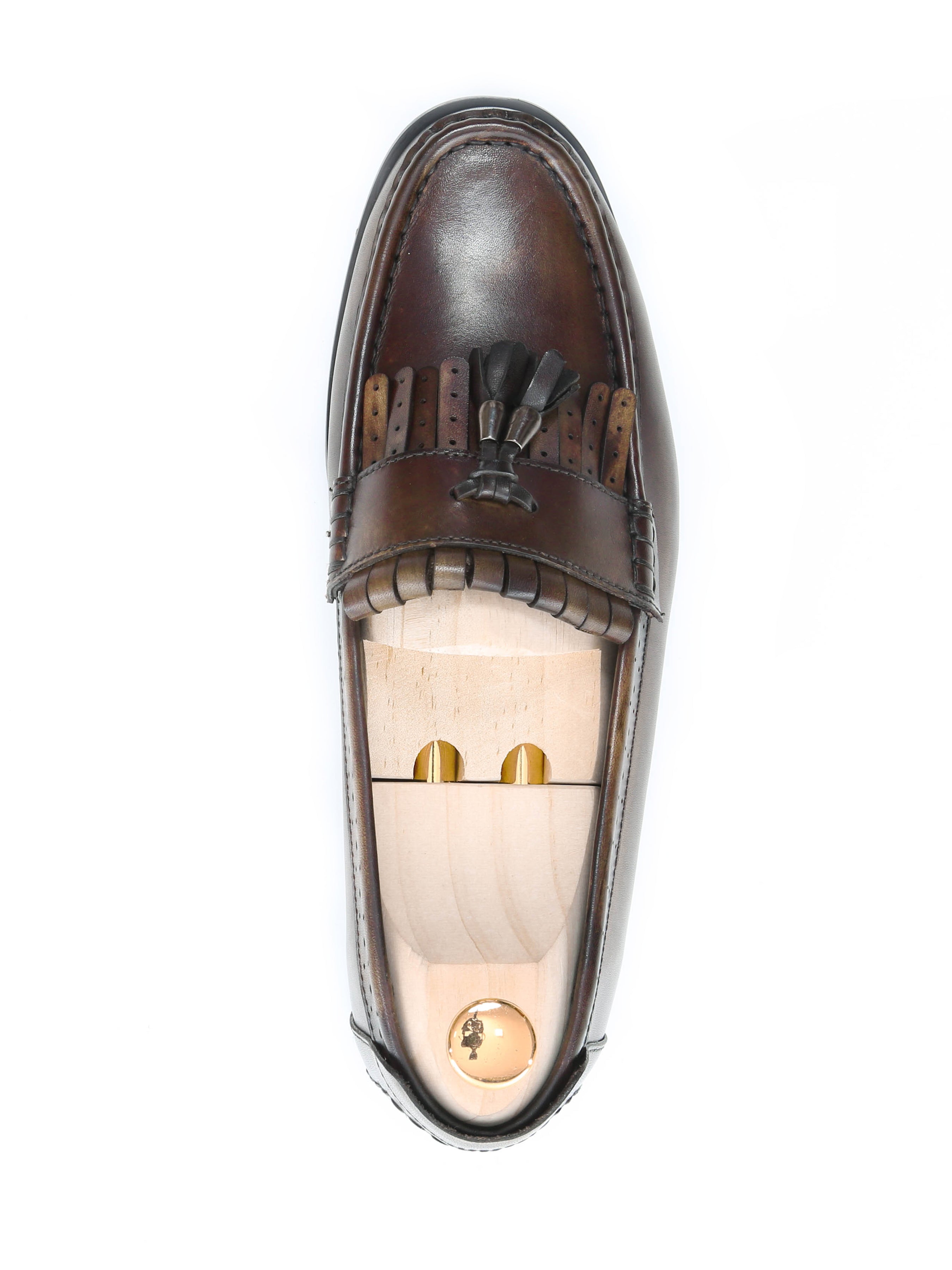 Handmade brown leather fringe loafer with tassels and a wooden shoe tree on white background