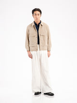 Men's beige corduroy jacket with navy shirt, white wide-leg pants, and black formal shoes