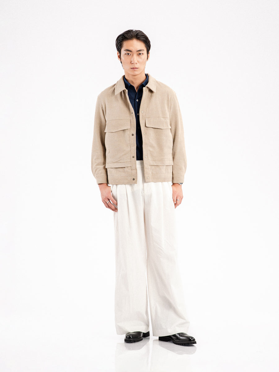 Men's beige corduroy jacket with navy shirt, white wide-leg pants, and black formal shoes