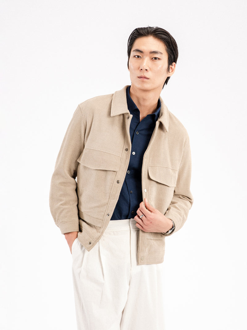 Men's beige corduroy jacket with navy shirt and white trousers, stylish casual wear