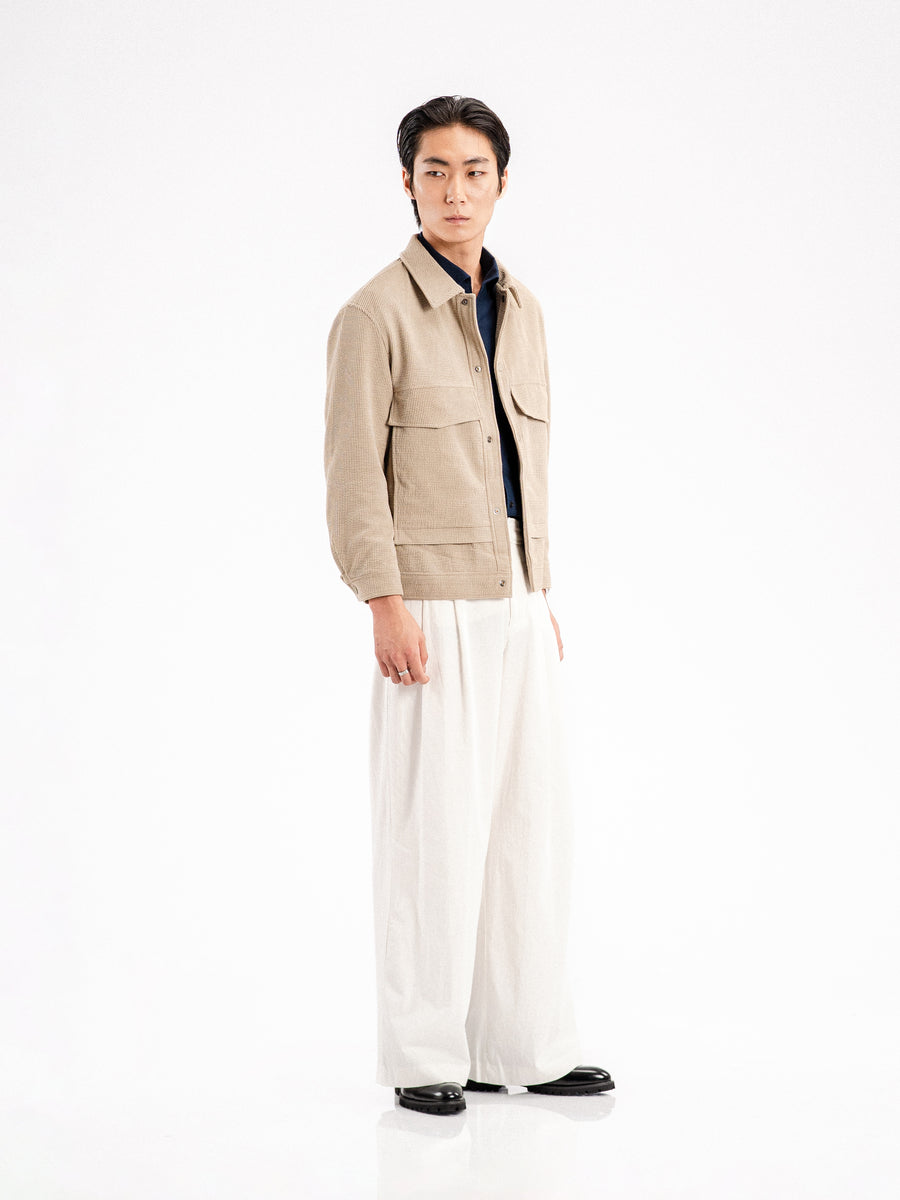 Men's beige corduroy jacket with navy shirt, white wide-leg pants, and black loafers for stylish casual wear