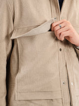 Beige corduroy jacket with front pocket, button closure, and man's hand wearing ring