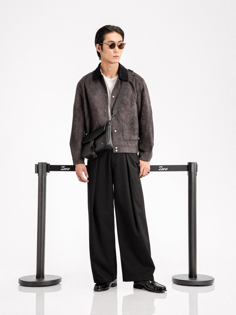 Man in stylish men's apparel: suede jacket, wide-leg trousers, loafers, and crossbody bag