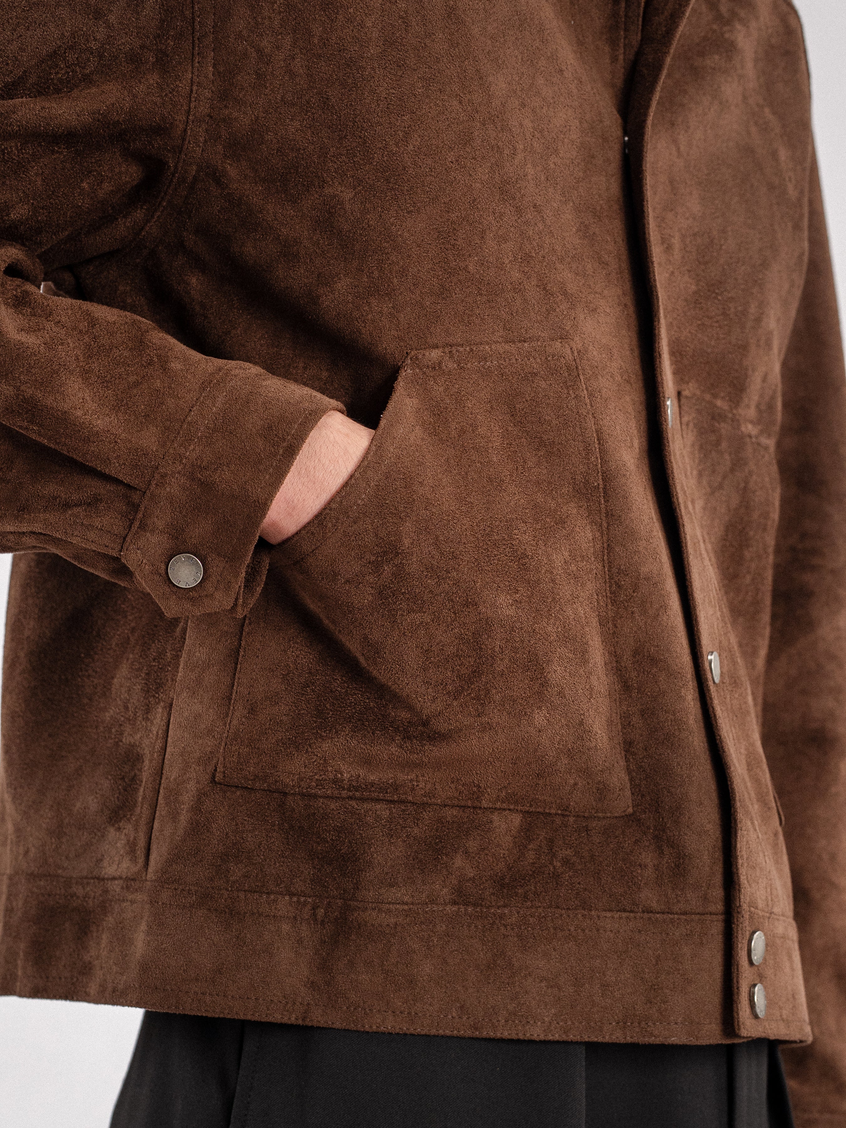 Brown suede men's jacket with button details and front pocket, styled with dark trousers