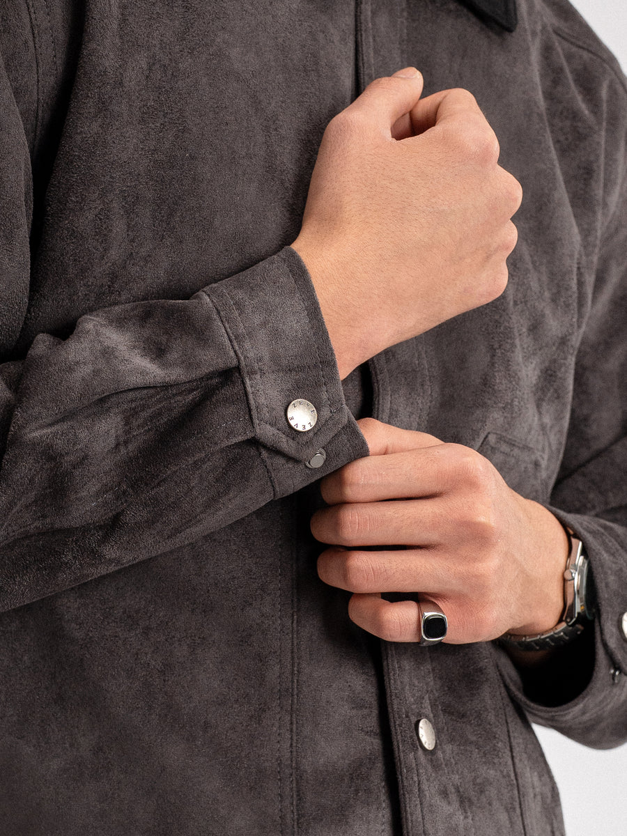 Men's dark gray suede shirt with branded buttons, styled with signet ring and watch for formal or casual wear.